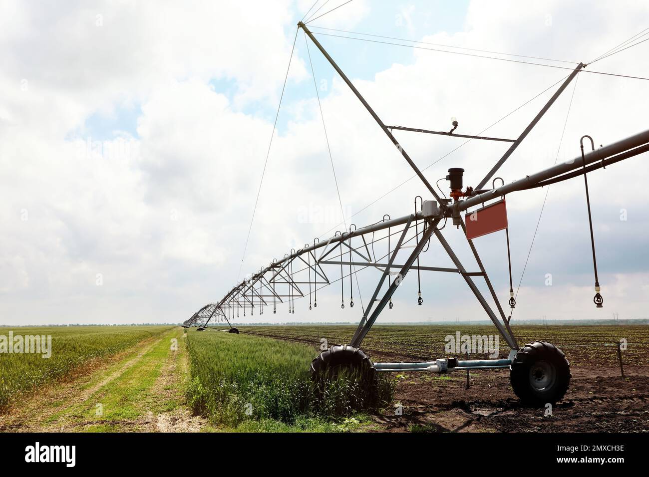 Modernes Bewässerungssystem im Feld unter bewölktem Himmel. Landwirtschaftliche Geräte Stockfoto