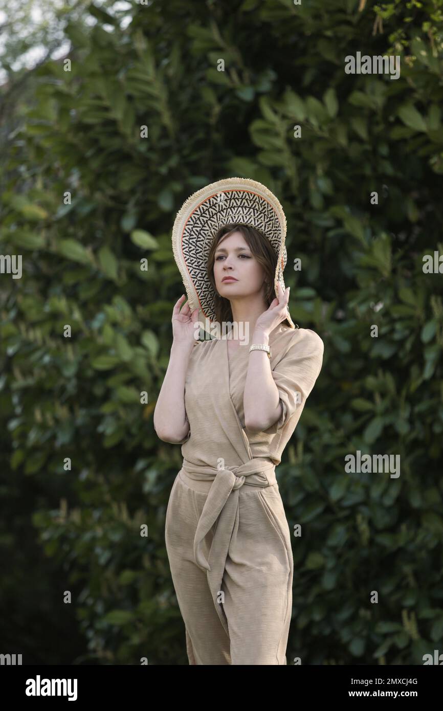 Außenporträt eines weiblichen Models in beigefarbenem Leinenkostüm Genießen Sie einen wunderschönen Sommertag im öffentlichen Park Stockfoto