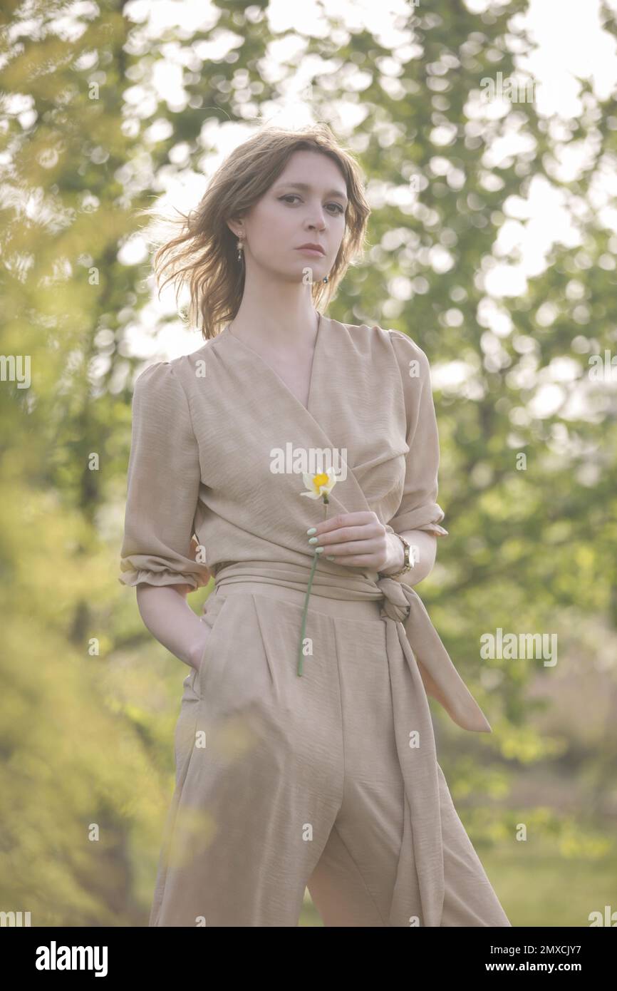 Außenporträt eines weiblichen Models in beigefarbenem Leinenkostüm Genießen Sie einen wunderschönen Sommertag im öffentlichen Park Stockfoto