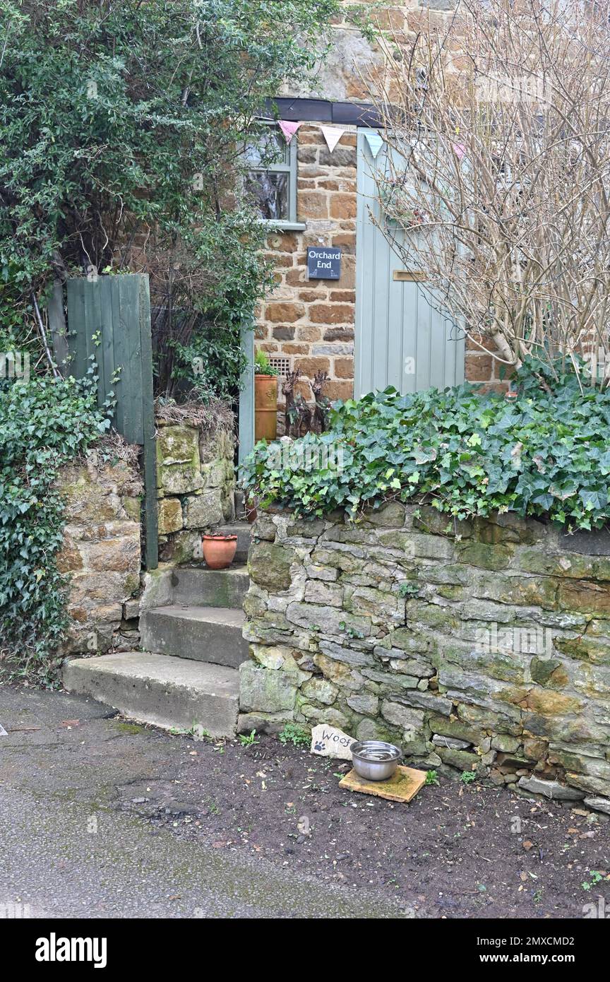 Eine Hundeschale voller Wasser wurde bequem vor einer Hütte im nördlichen Dorf Hook Norton in Oxfordshire aufgestellt, um Hunde an sie weiterzugeben Stockfoto