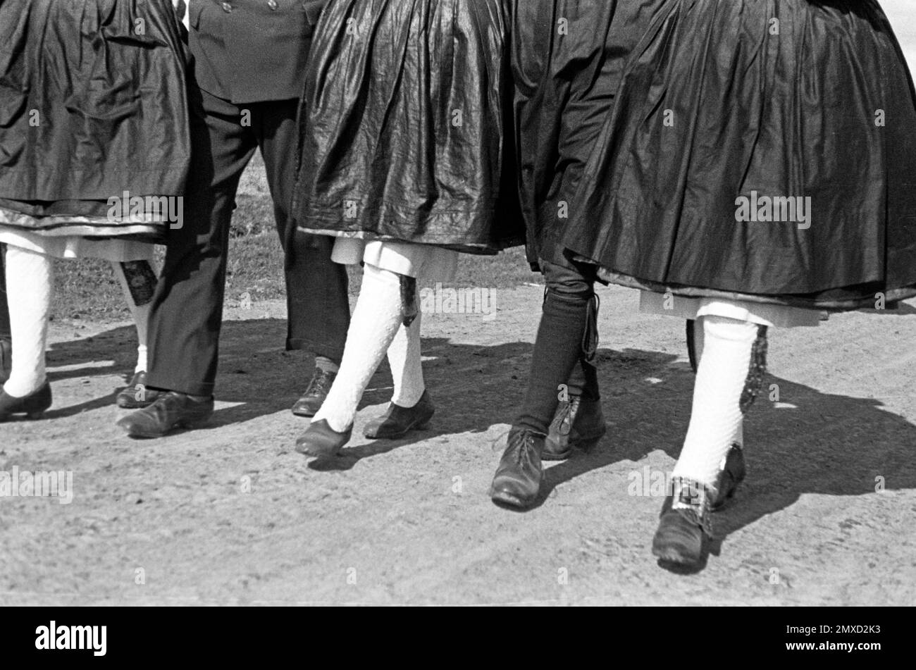 Junge Leute in Tracht laufen eine Landstraße im Schwalm-Eder-Kreis in Hessen entlang, 1938. Junge Menschen in traditioneller Kleidung auf einer Landstraße in der Region Schwalm-Eder in Hessen, 1938. Stockfoto