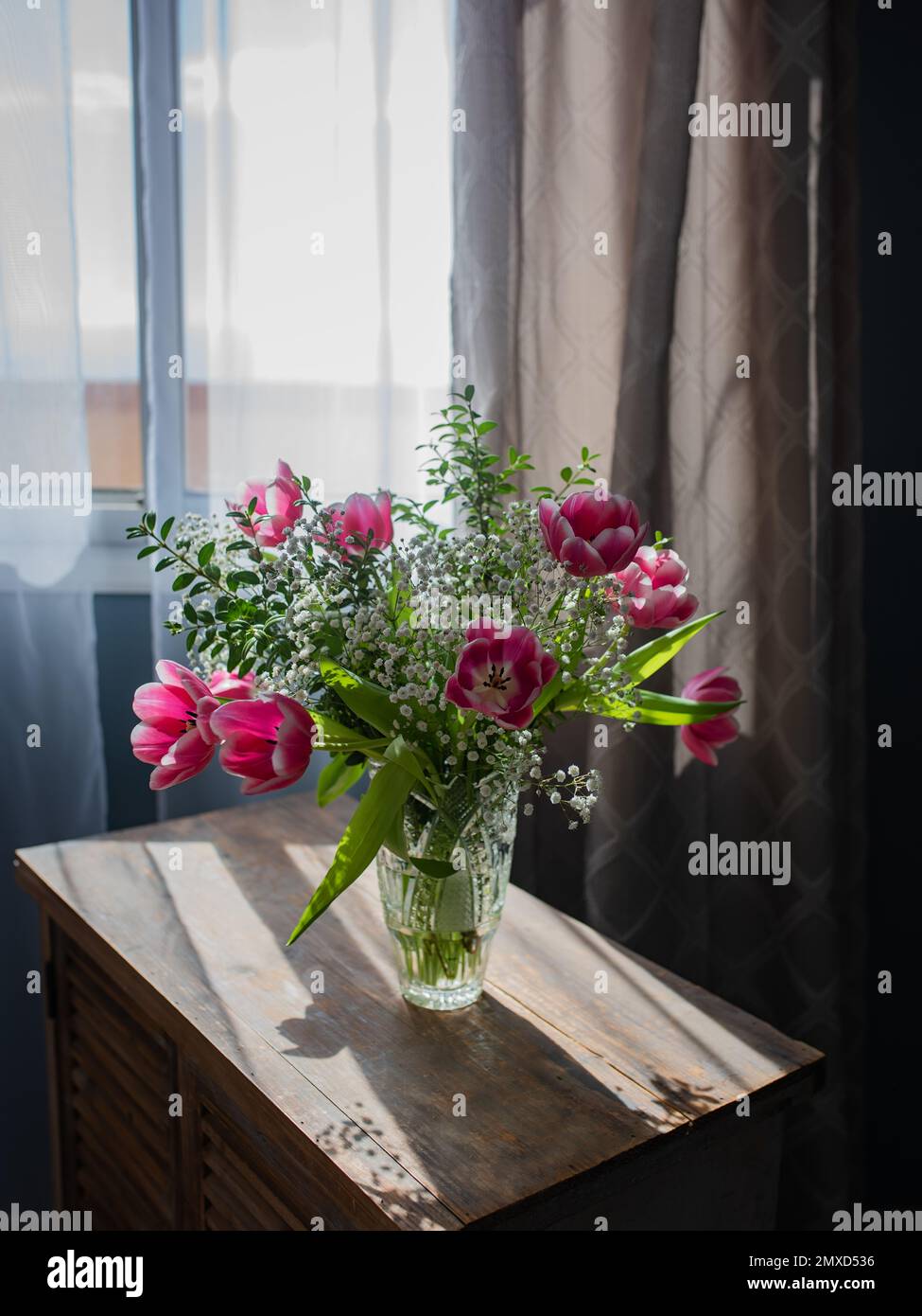 Wunderschöner Strauß von Tulpen in Glasvase auf weißem Marmortisch. Platz für Text. Stockfoto