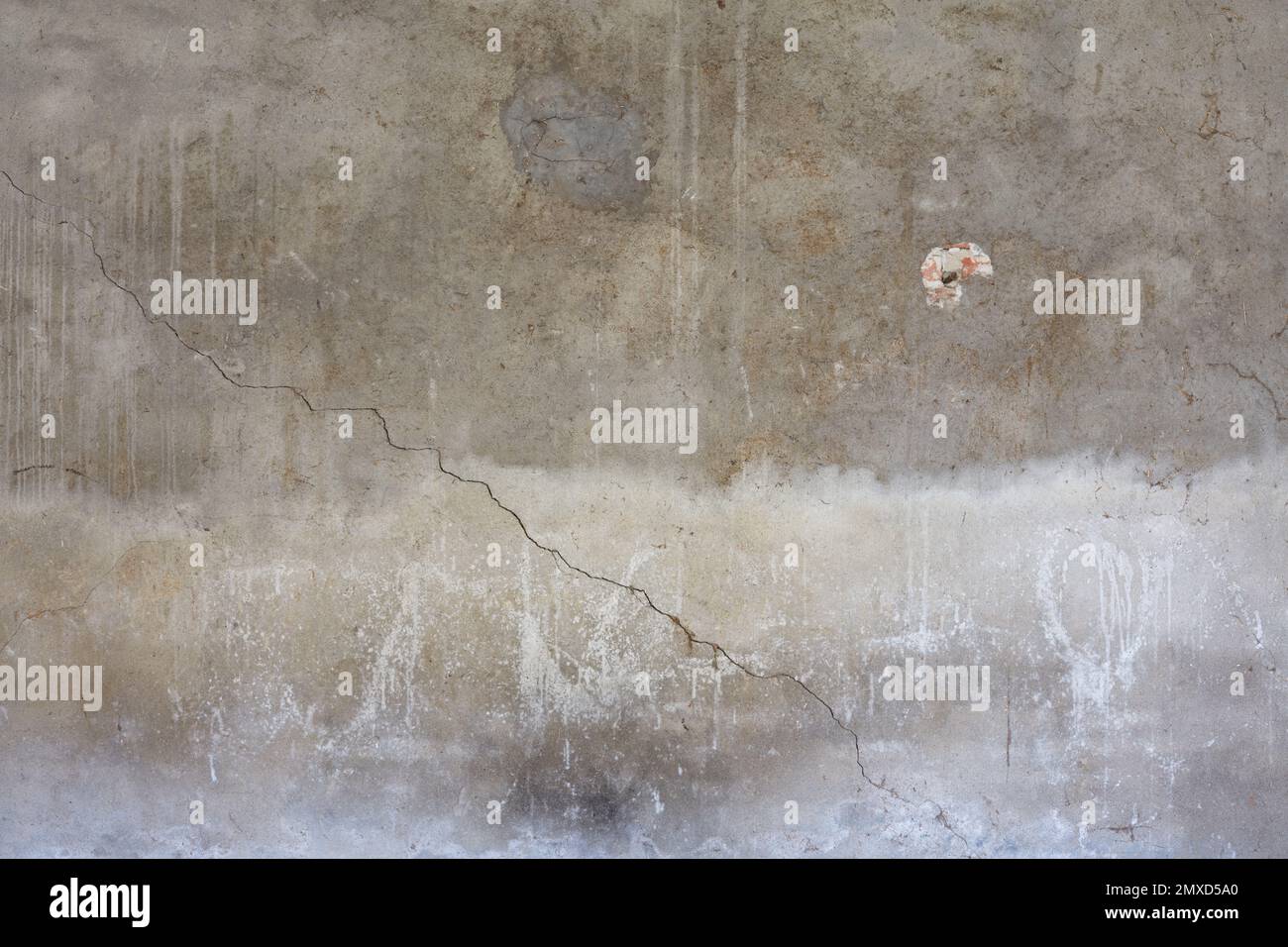 Graue Betonwand mit Rissen und weißen Flecken strukturierter Hintergrund Stockfoto
