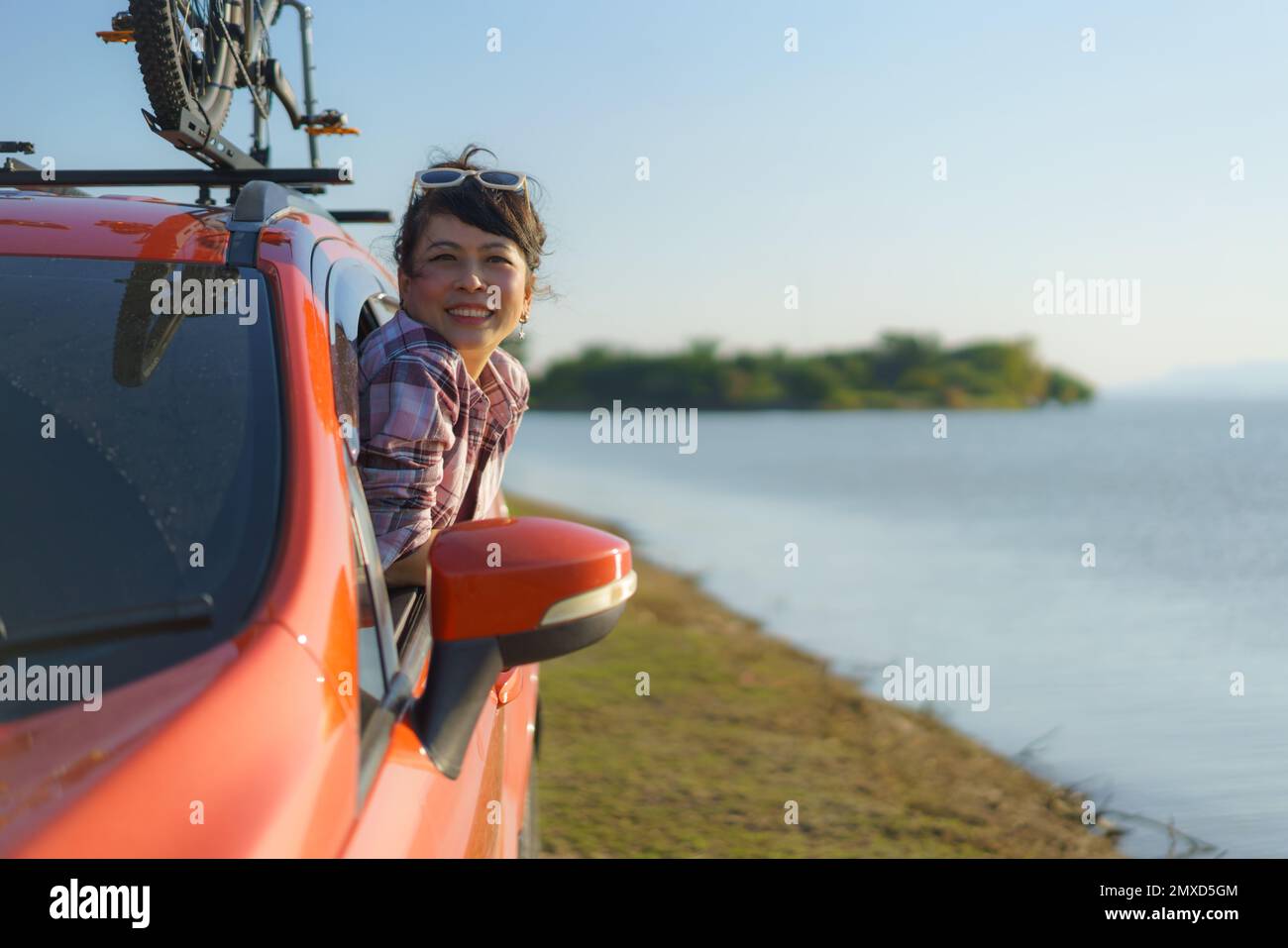 Eine Asiatin springt beim Camping aus dem Autofenster und atmet frische Luft Stockfoto