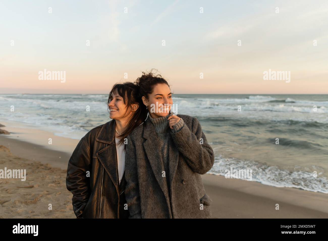 Glückliche Frauen stehen am Strand während des Sonnenuntergangs in Barcelona Stockfoto