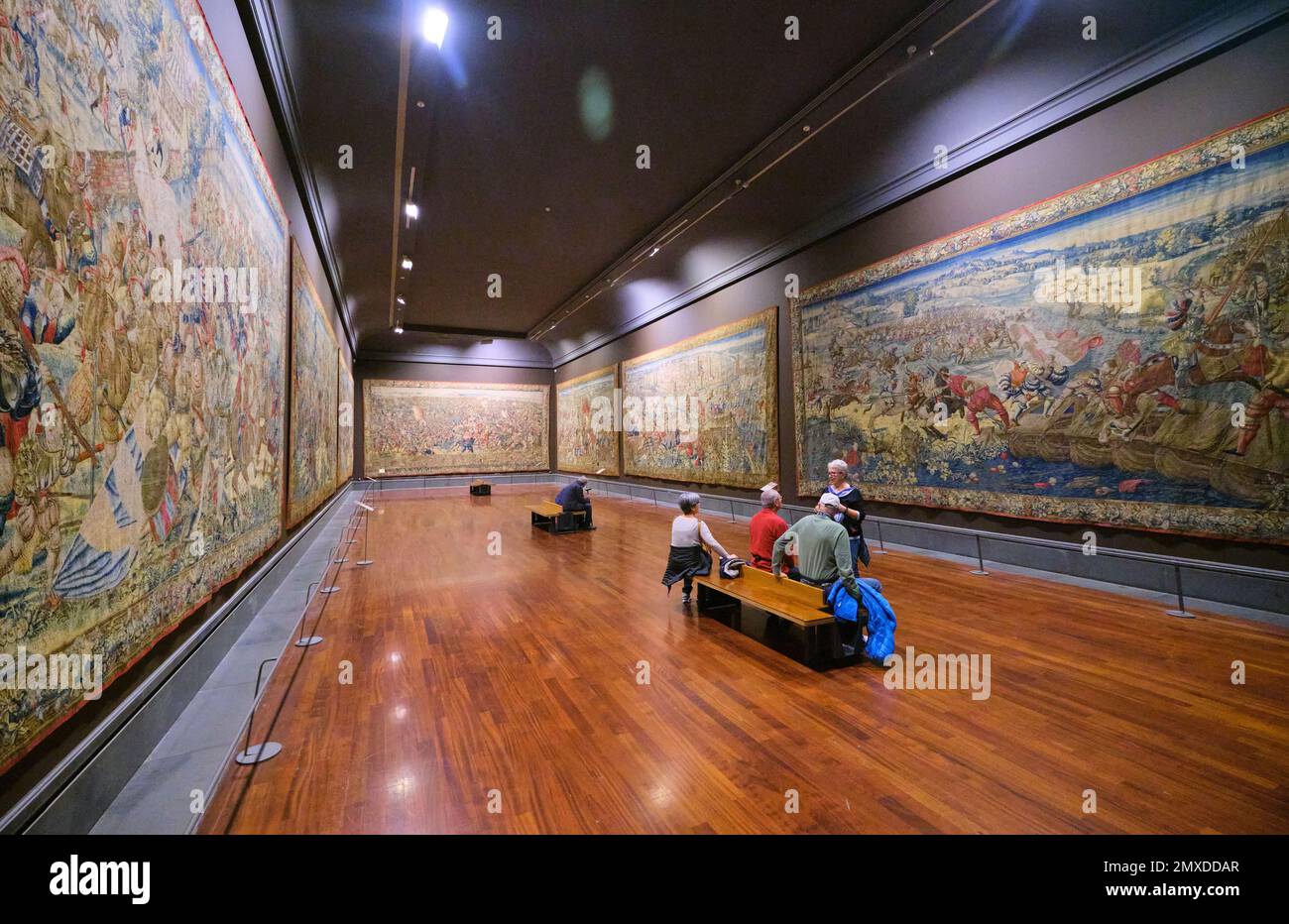 Besucher genießen einen der Räume mit großen Wandteppichen. Viele Textilien bieten aufwändige Kampfszenen. Im Kunstmuseum, Museo e Real Bosco Stockfoto