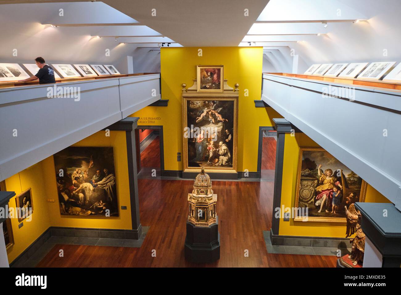 Blick auf einen zweistöckigen Galeriebereich mit religiösen Gemälden und einem kleineren Arbeitsbereich. Im Kunstmuseum, Museo e Real Bosco di Capodimonte, in Neapel Stockfoto