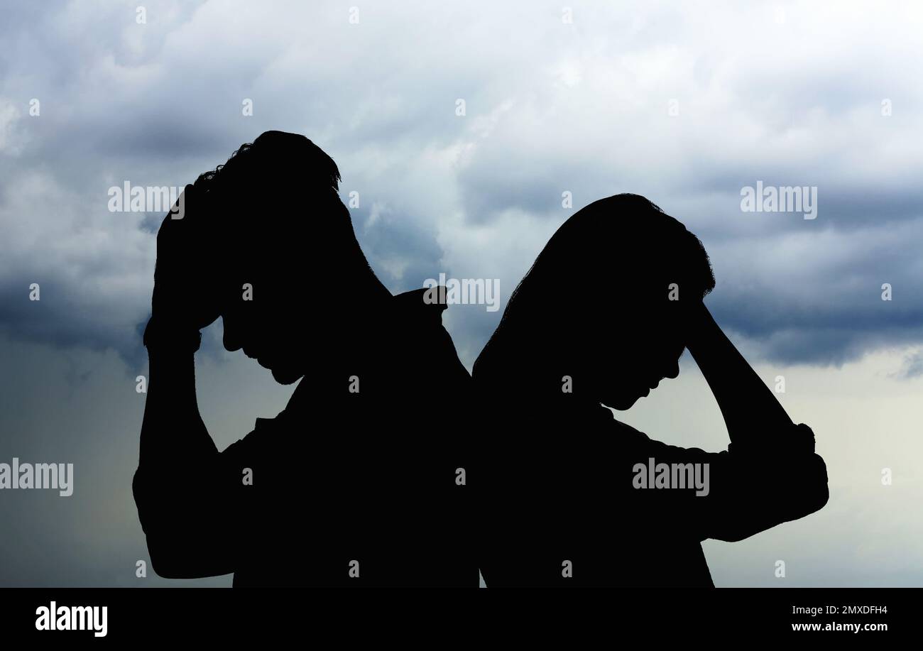 Silhouetten eines streitenden Paares gegen den Himmel mit schweren Regenwolken. Beziehungsprobleme Stockfoto