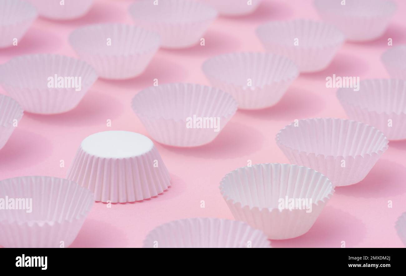 Nahaufnahme flach liegend weiches, helles, weißes Papier rund Cupcake Behälter auf süßrosa minimalem Hintergrund. Idee für Dessert Hintergrund, Backwaren Zubehör Sho Stockfoto