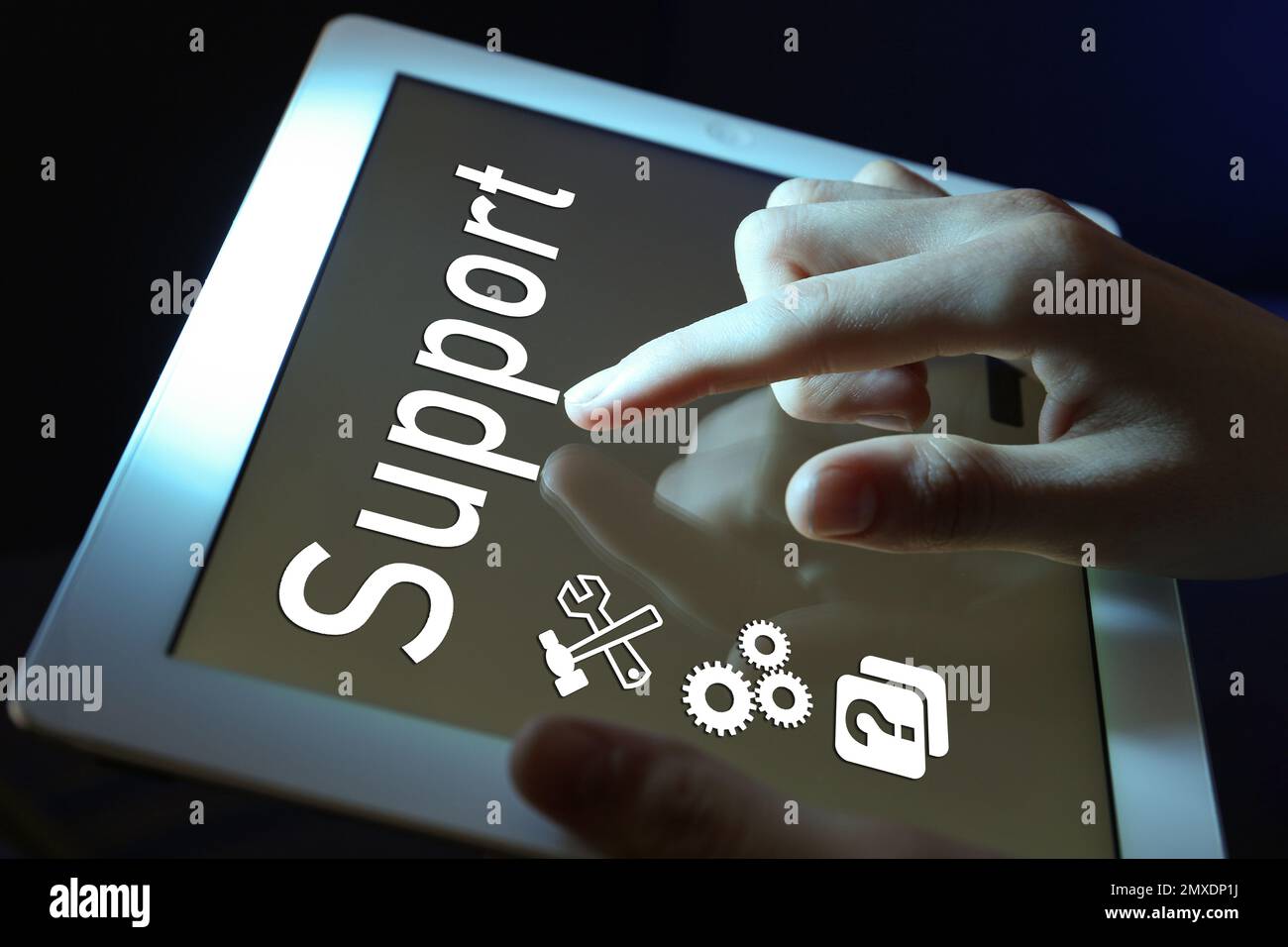 Frau, die ein Tablet auf dunklem Hintergrund benutzt, Nahaufnahme. Technischer Support Stockfoto