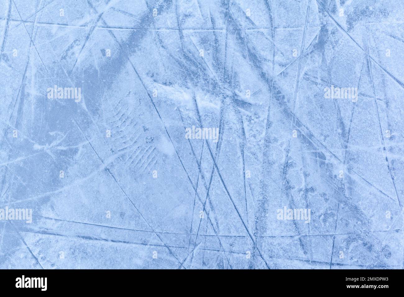 Leere Eisbahn mit Schlittschuhspuren nach der Sitzung im Freien. Eislaufbahn Textur mit Schnee bei Tageslicht bedeckt. Nahaufnahme von blauem Eislaufboden, CO Stockfoto