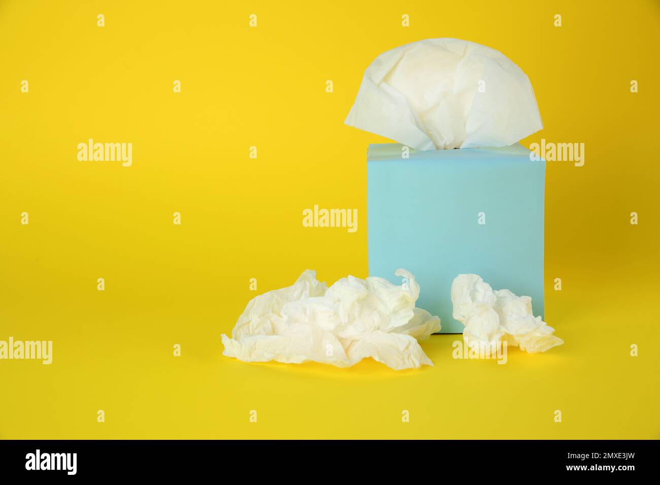 Gebrauchte Papiertücher und Schachtel auf gelbem Hintergrund. Platz für Text Stockfoto