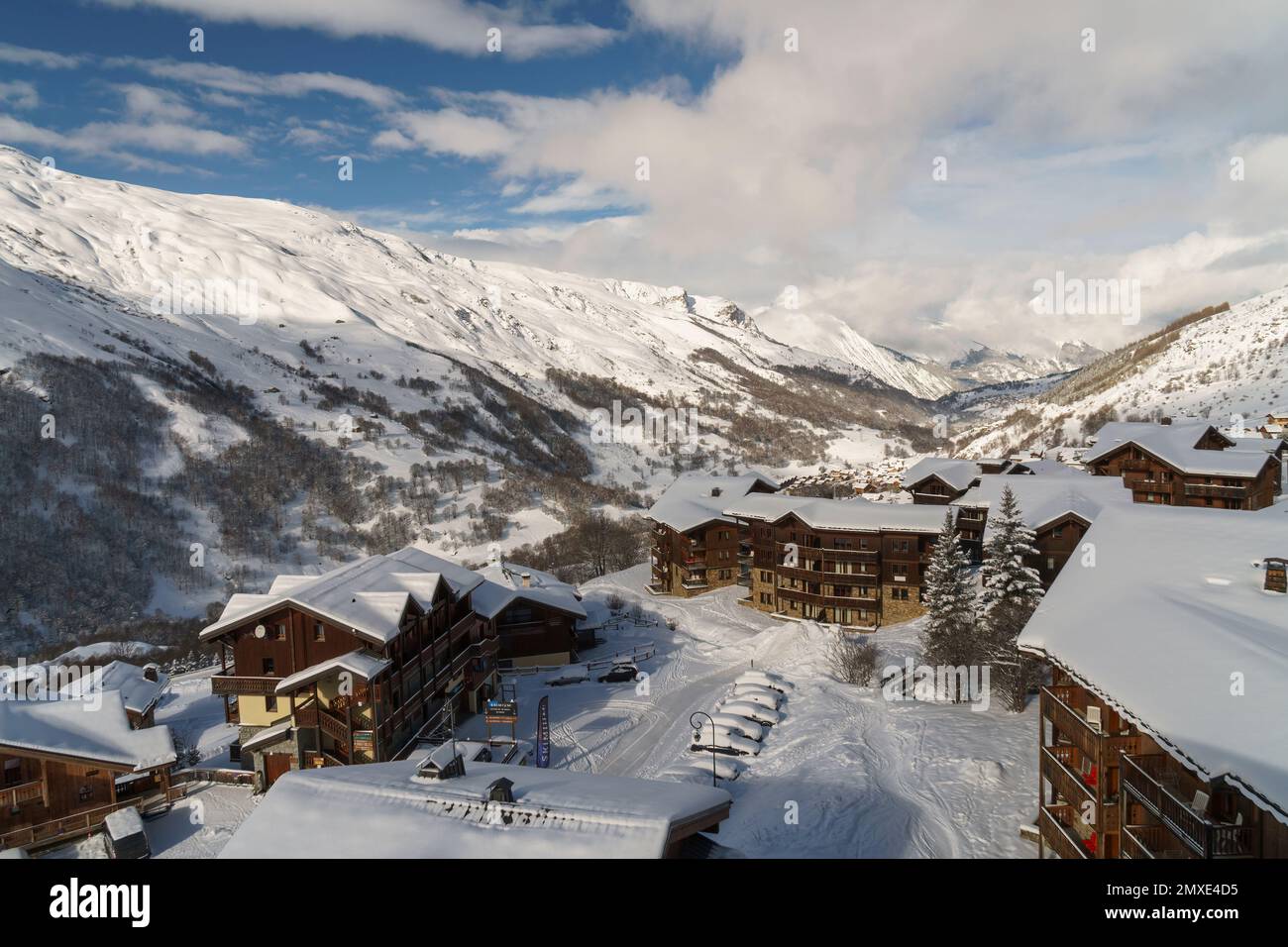 Dachhütten in Les Menuires nach einem neuen Schneefall Anfang 2023. Blauer Himmel und Berge im Hintergrund. Stockfoto