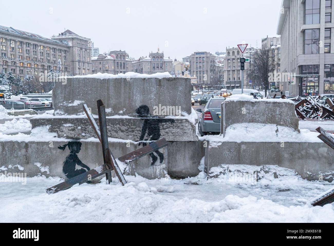 Ein Junge und ein Mädchen schaukeln auf einem PanzerabwehrIgel - Banksy Graffiti in Kiew, Ukraine Stockfoto