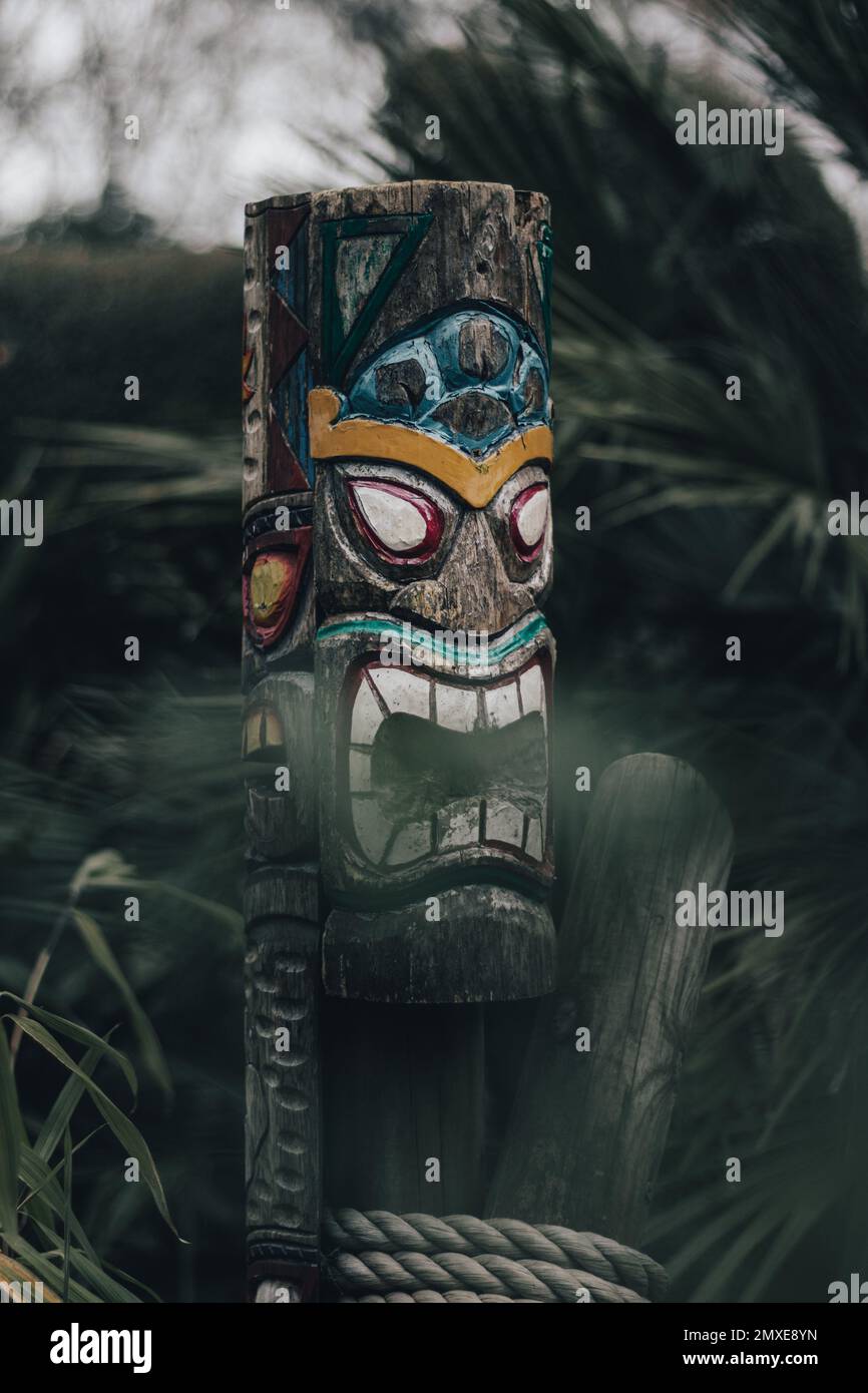 Eine Nahaufnahme einer seltsamen und furchteinflößenden Menschenfigur des Totemismus mit dem Hintergrund einer Tanne Stockfoto