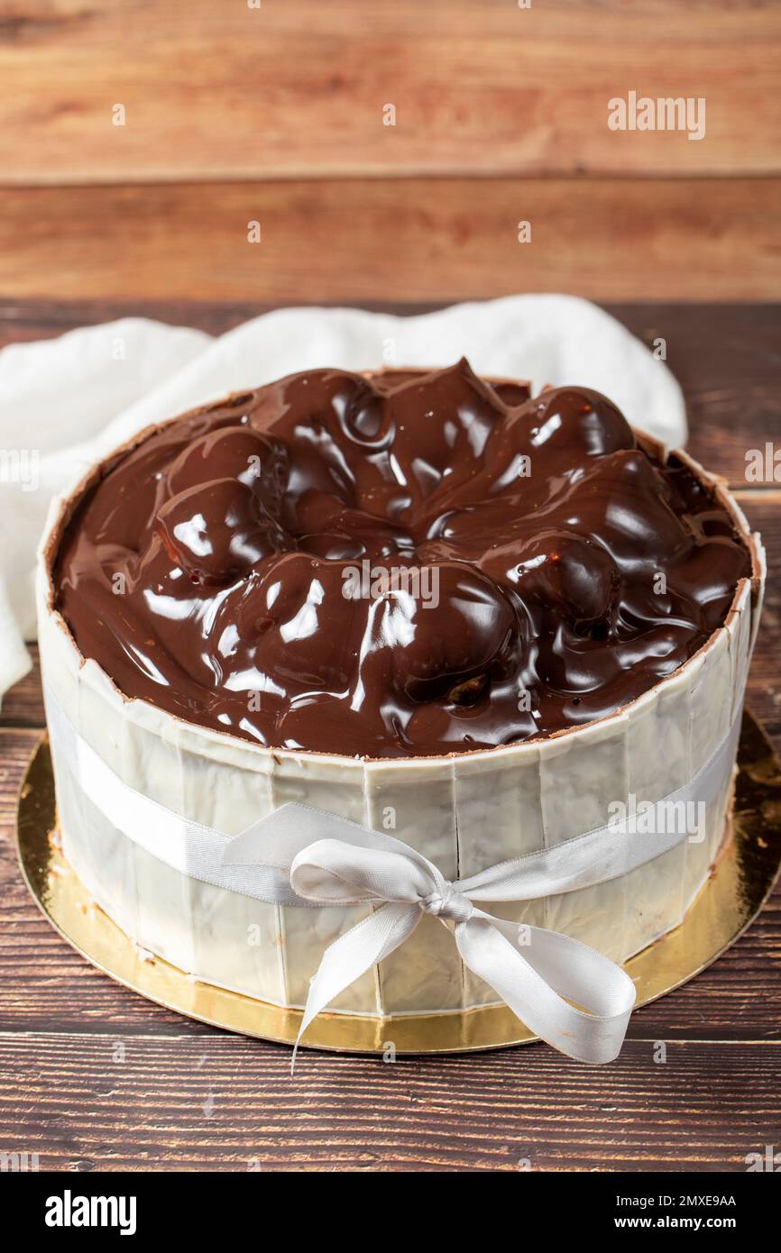 Profiterole-Kuchen. Kuchen mit Profiteroles, umgeben von weißer Schokolade auf Holzhintergrund. Schließen Stockfoto