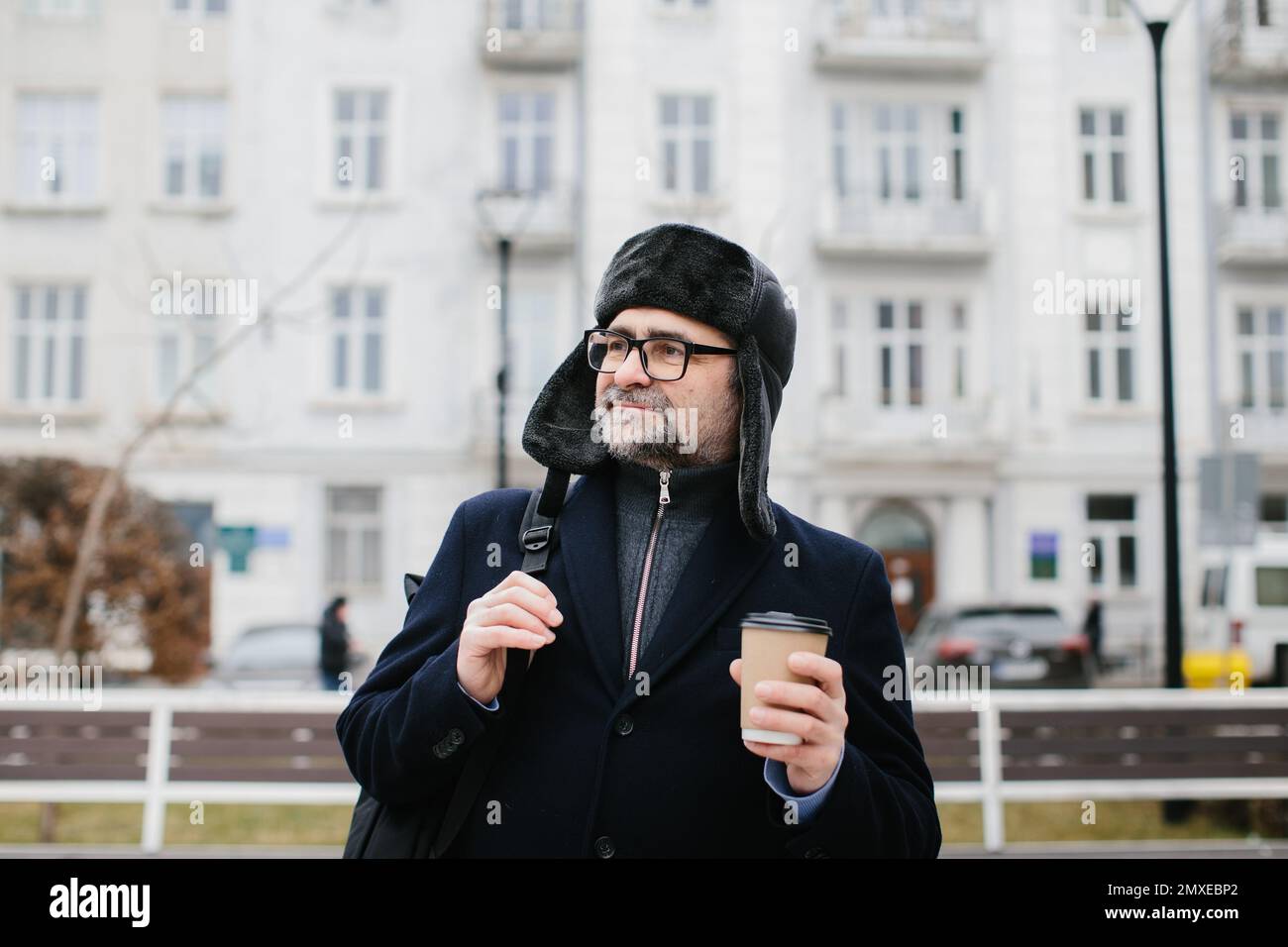 Seniorenmann genießt am Wochenende einen Spaziergang in der Winterstadt. Das Konzept des Stadtlebens und der Erholung. Stockfoto