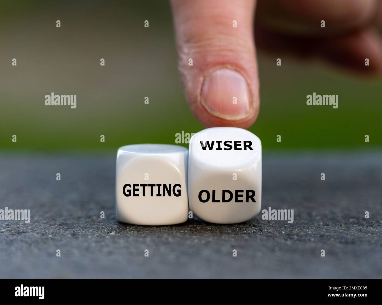 Die Hand würfelt und ändert den Ausdruck „älter werden“ in „weiser werden“. Stockfoto