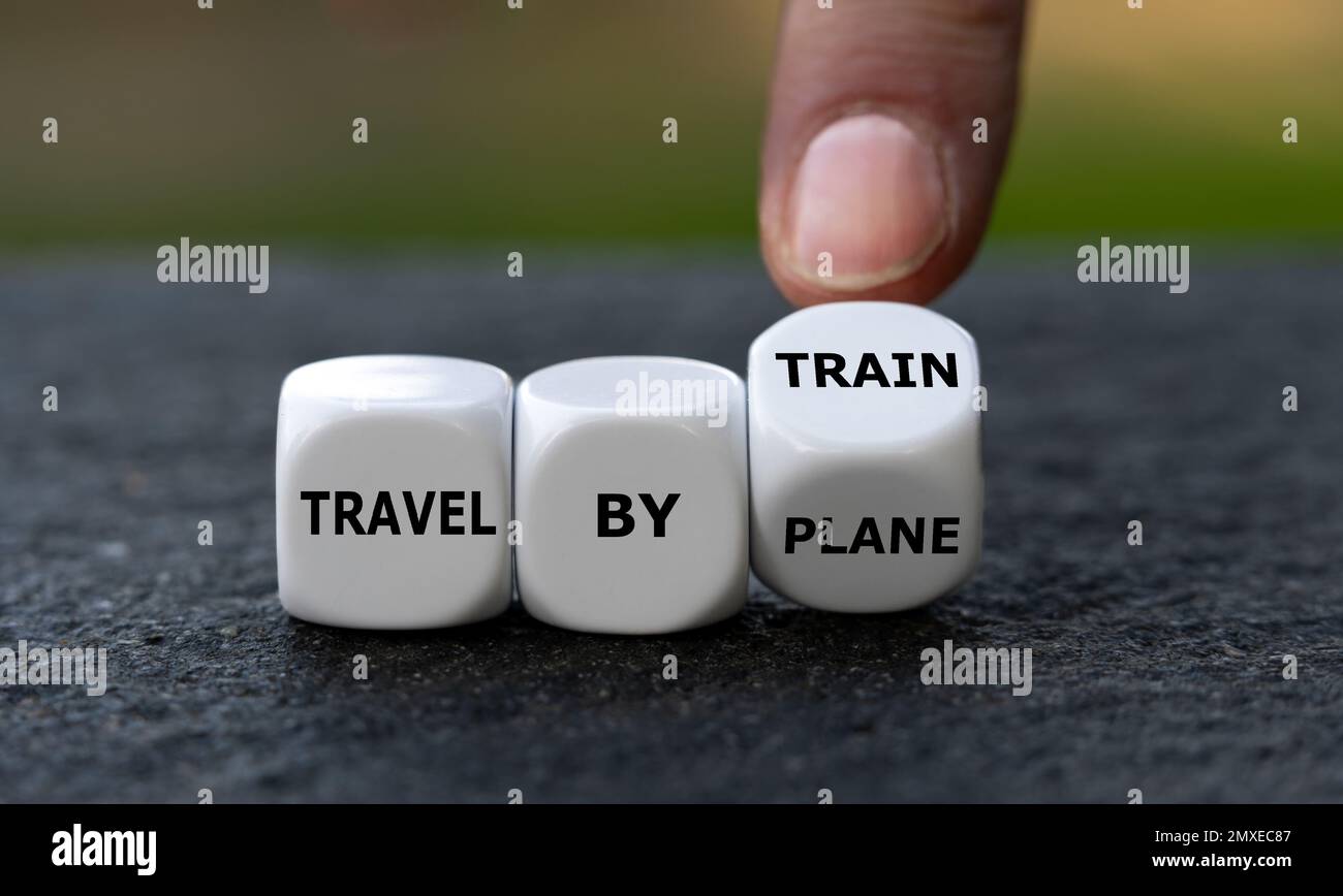 Die Hand dreht Würfel und ändert den Ausdruck „mit dem Flugzeug reisen“ in „mit dem Zug reisen“. Symbol zur Verringerung der Emissionen durch Zugreisen anstelle von tra Stockfoto