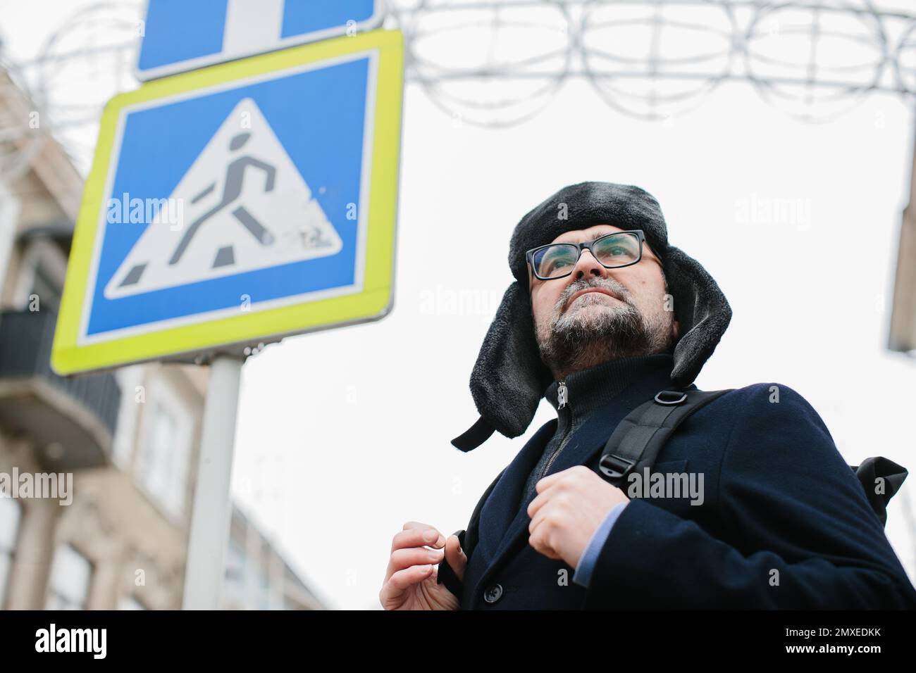 Seniorenmann genießt am Wochenende einen Spaziergang in der Winterstadt. Das Konzept des Stadtlebens und der Erholung. Stockfoto