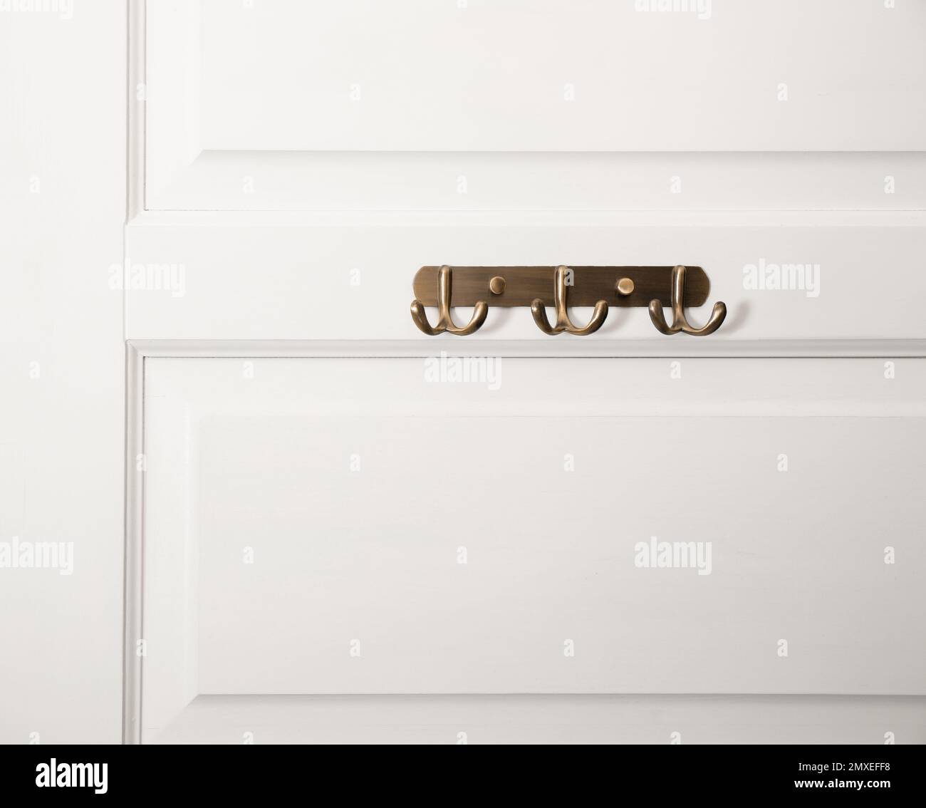 Weiße Tür mit leeren Kleiderhaken aus Metall Stockfoto