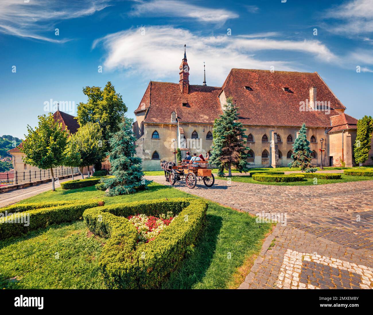 Fahrt in einer Pferdekutsche in Sighisoara. Wunderbarer Sommerblick auf die Evangelische Kirche. Sonnige Morgenszene der mittelalterlichen Stadt Transylvan Stockfoto