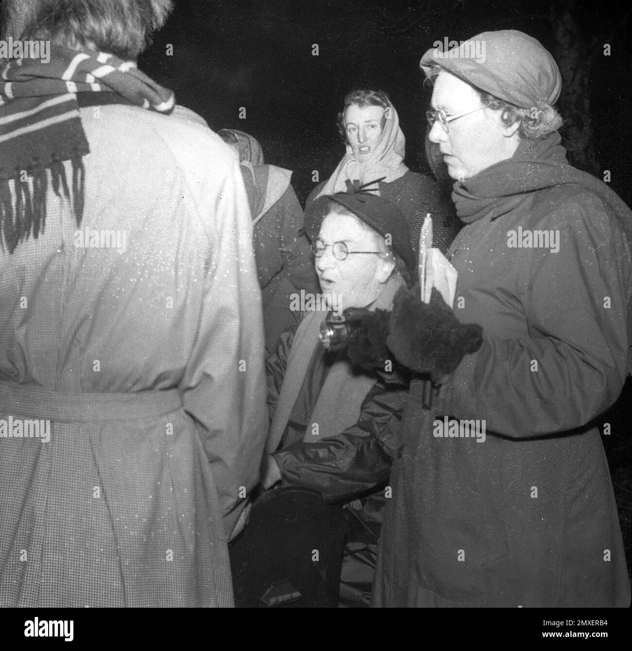 1955, historisch, Winter und Schneeflocken, die auf weiblichen Sängern vor einem Klavier stehen, Cambridge, England, Großbritannien. Stockfoto