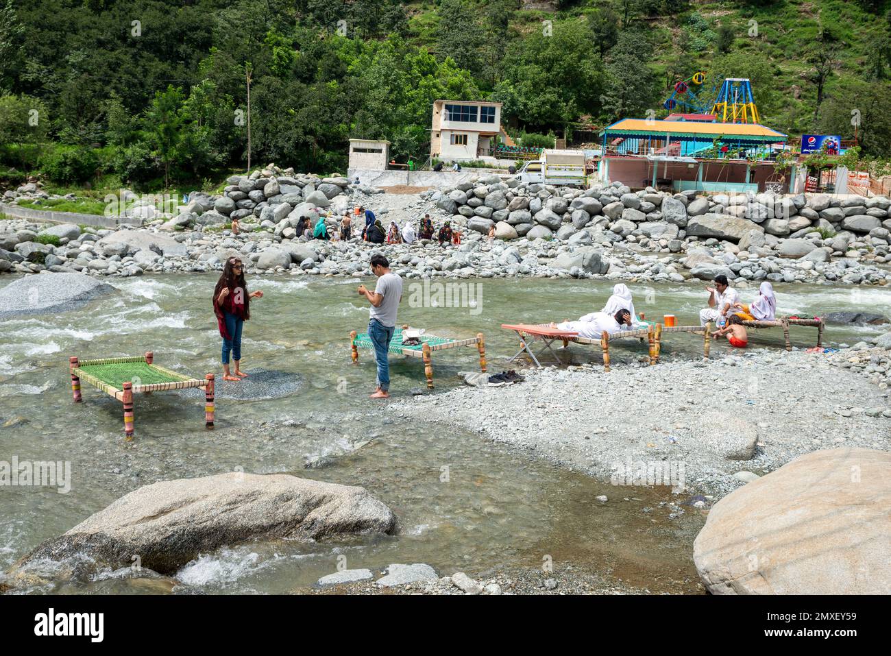 Die pakistanischen Menschen genießen im Sommer frische Charpai (Holzbetten) am Ufer des SWAT River, SWAT Valley, Pakistan Stockfoto