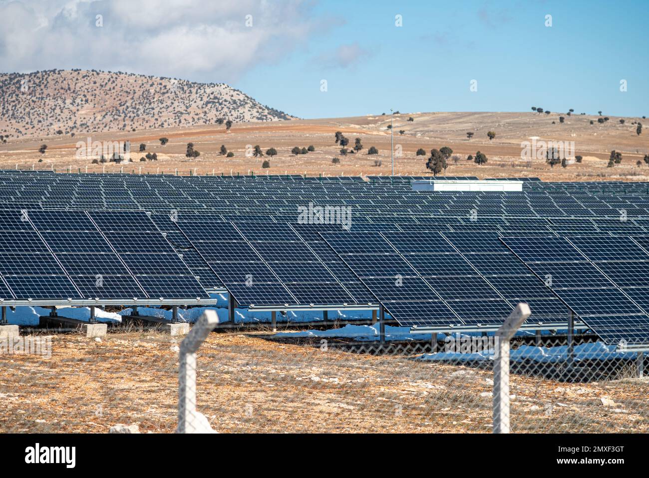 Solarfeld mit eingezäunten Sonnenkollektoren bei Sonnenuntergang Stockfoto