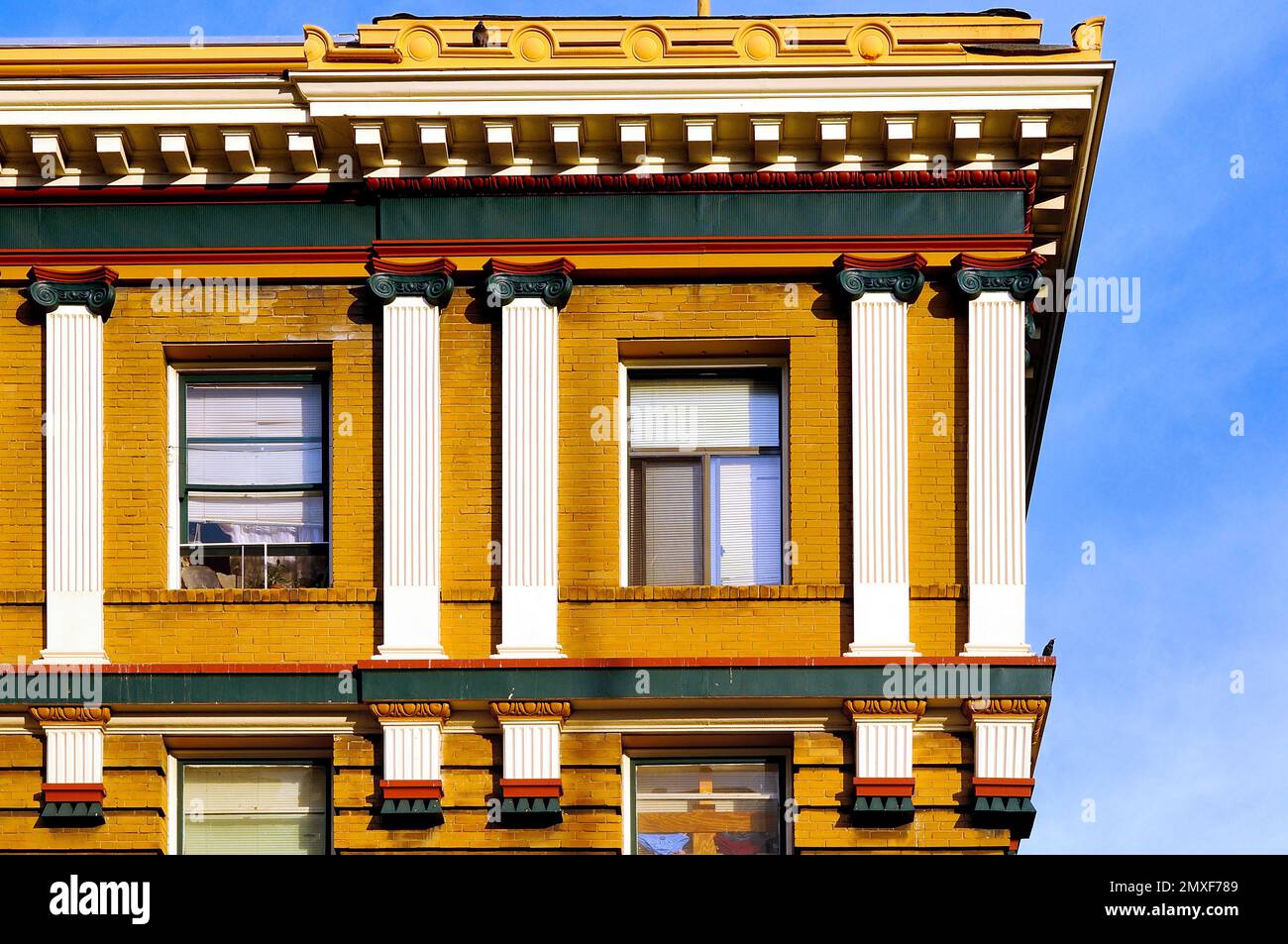 Das historische Gebäude verfügt über eine kunstvoll verzierte Fassade mit klassischen Säulen, gelbem Mauerwerk und detaillierten dekorativen Elementen, die elegante Architektur verkörpern Stockfoto