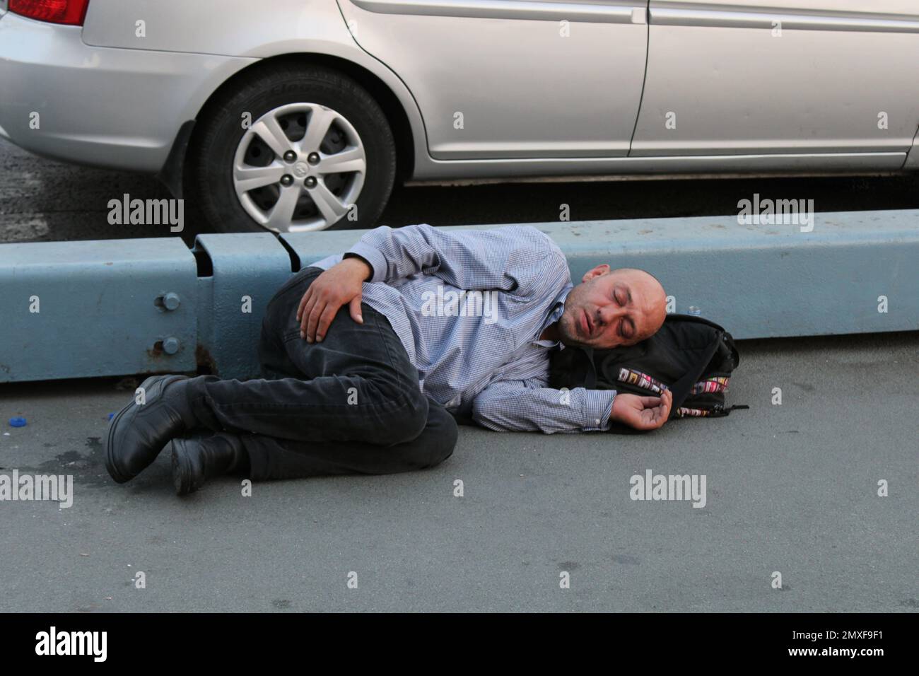 Ein Obdachloser, der auf dem Bürgersteig liegt. Stockfoto