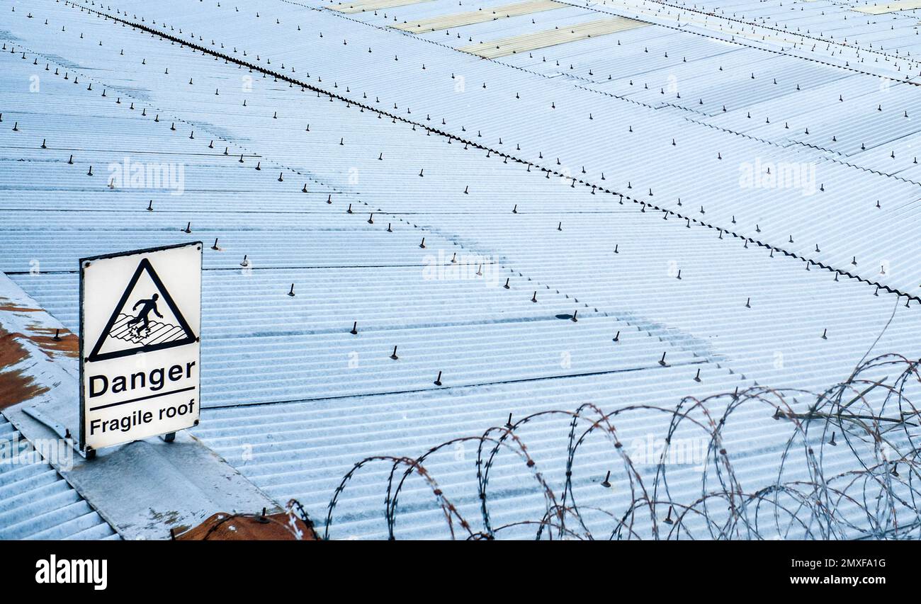 Schild „Gefahr zerbrechliches Dach“ auf Wellendach und Stacheldraht kentish Stadt Stockfoto