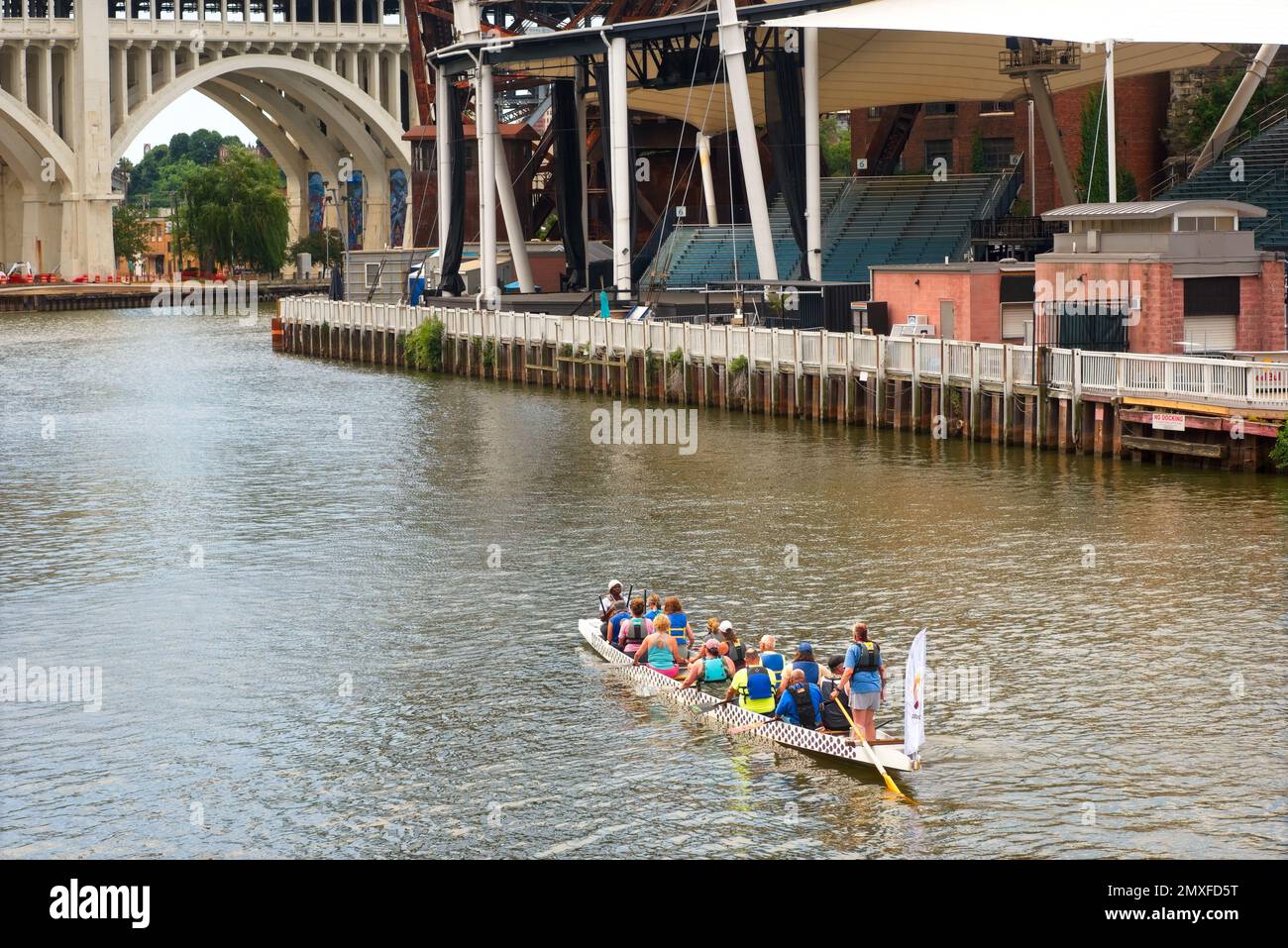 Eine Kajakcrew paddelt den Cuyahoga River hinauf, vorbei an der Nautica Sound Stage, einem beliebten Veranstaltungsort für Open-Air-Konzerte und -Shows. Stockfoto