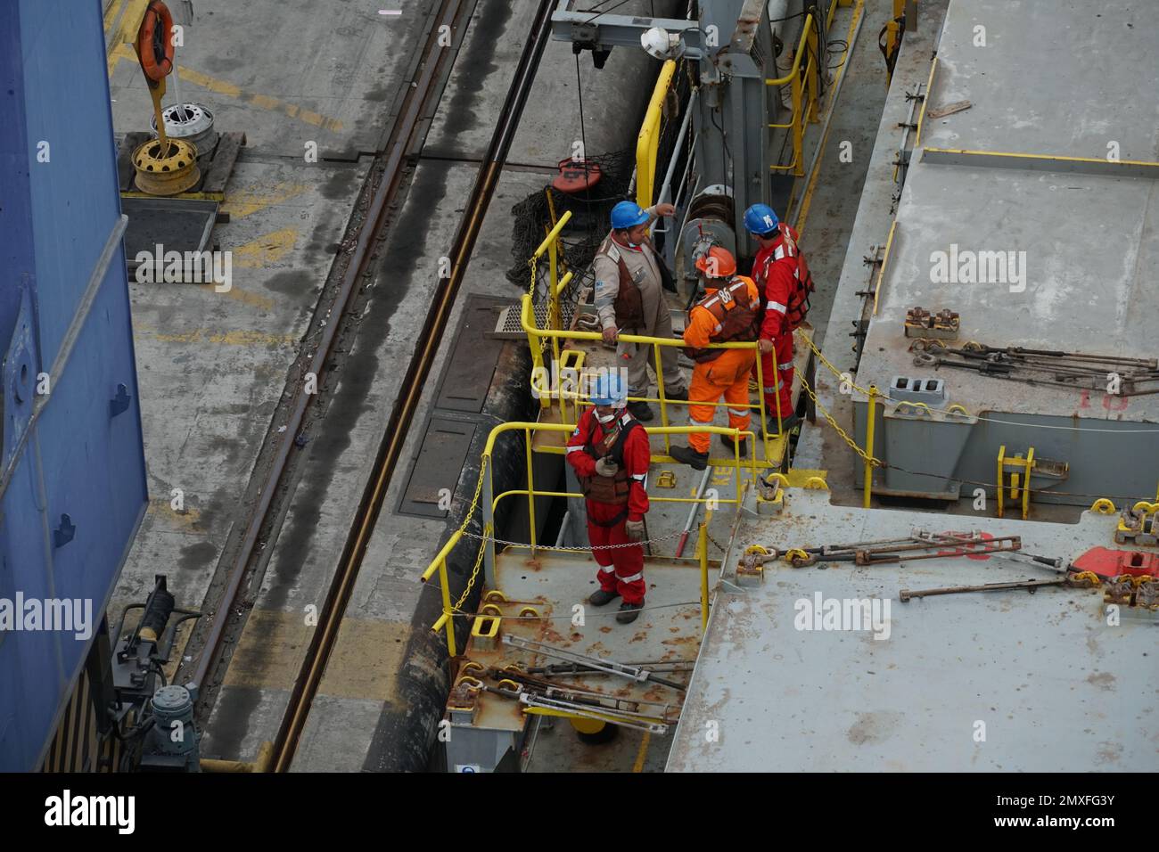 Sie tragen Schutzkleidung und Helme und besprechen den Frachtbetrieb im Containerterminal. Stockfoto