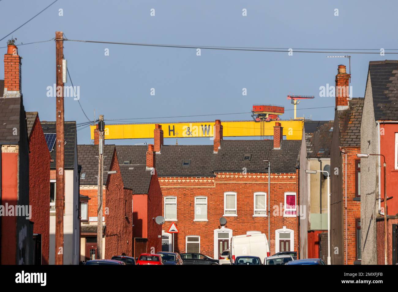 Harland & Wolff Industrial Belfast. Der gelbe Krupp-Gantrykran über einer Reihe von Terrassen beherbergt an sonnigen Tagen Kaminkübel auf dem Dach im Südosten von Belfast. Stockfoto