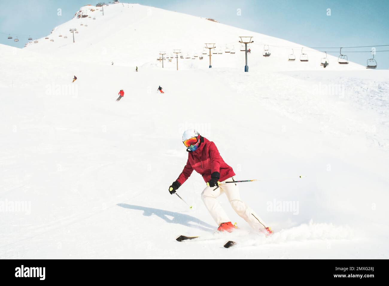 Junge Skifahrerin in roter Skijacke und weißen Hosen im Skigebiet Gudauri Stockfoto