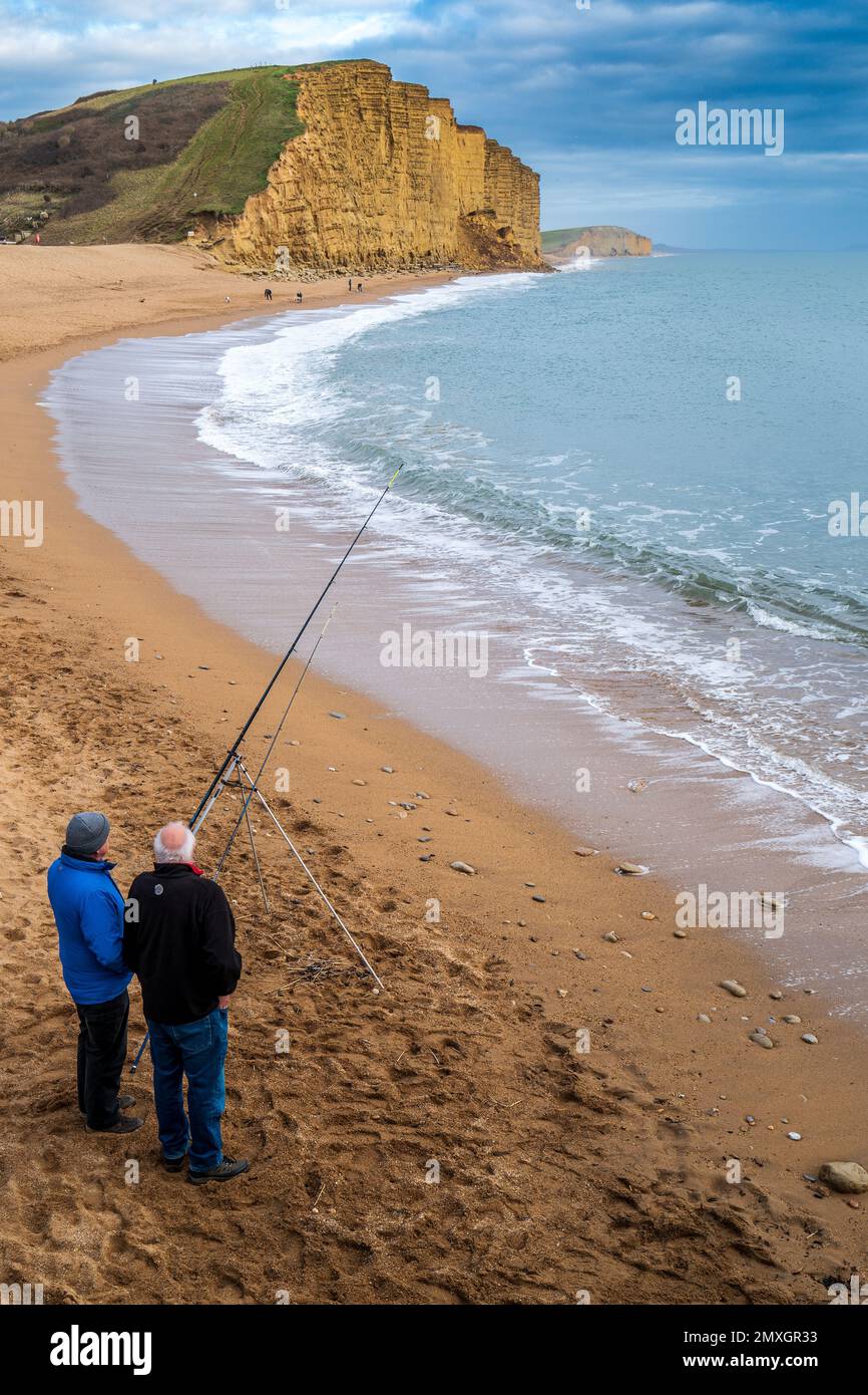 Zwei Angler am West Bay Beach mit dem Einsturz der Klippen im Februar 2023 im Hintergrund Stockfoto