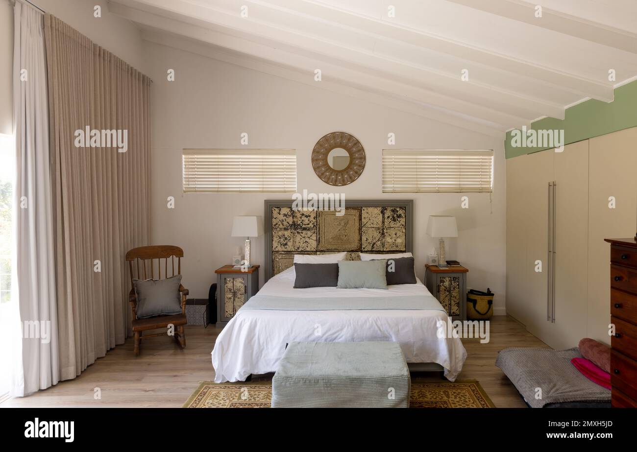 Elektrische Lampen auf Nachttischen neben einem sauberen Bett mit Stuhl und Ottomane im modernen Schlafzimmer, Kopierbereich Stockfoto