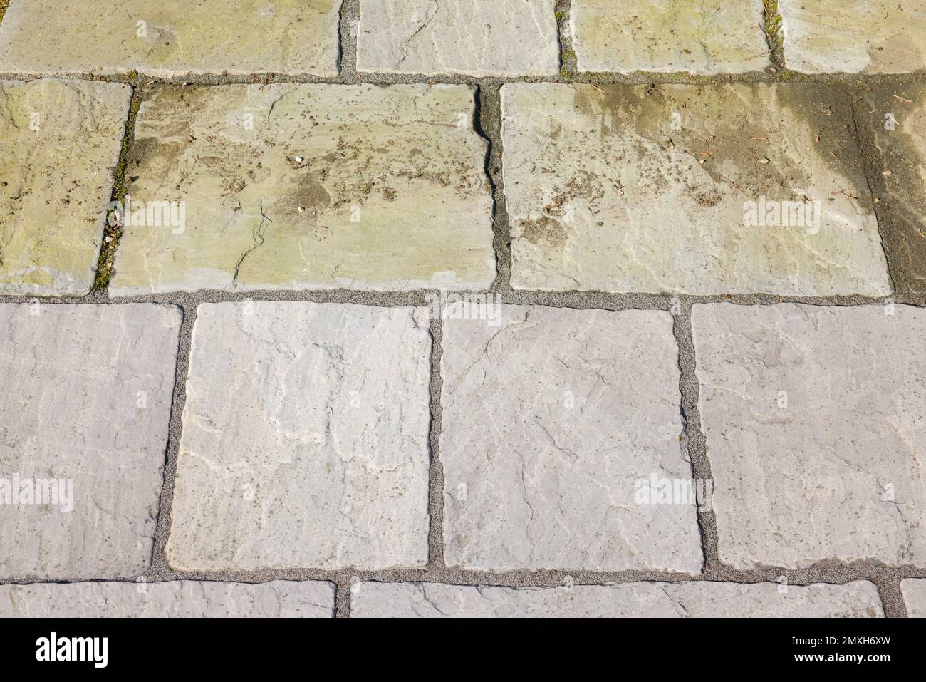 Reinigung der Gartenterrasse. Sandsteinpflaster vor und nach dem Waschen mit dem Hochdruckreiniger, UK. Stockfoto