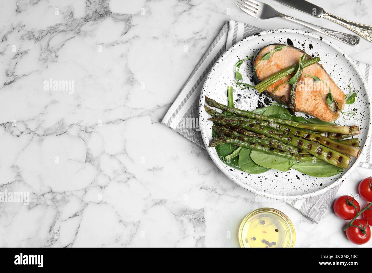 Leckeres Lachssteak mit gegrilltem Spargel auf einem weißen Marmortisch, flach liegend. Platz für Text Stockfoto