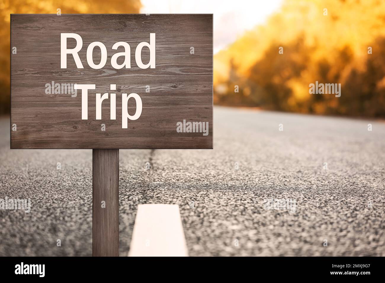 Holztafel mit Inschrift Road Trip auf Asphalt Highway Stockfoto