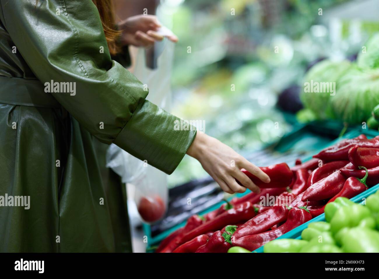 Eine Frau im Supermarkt, die frisches Gemüse pflückt, um im Supermarkt zu kochen, zu Hause zu Abend zu kochen, auf dem Markt einkaufen, rote Paprika Stockfoto