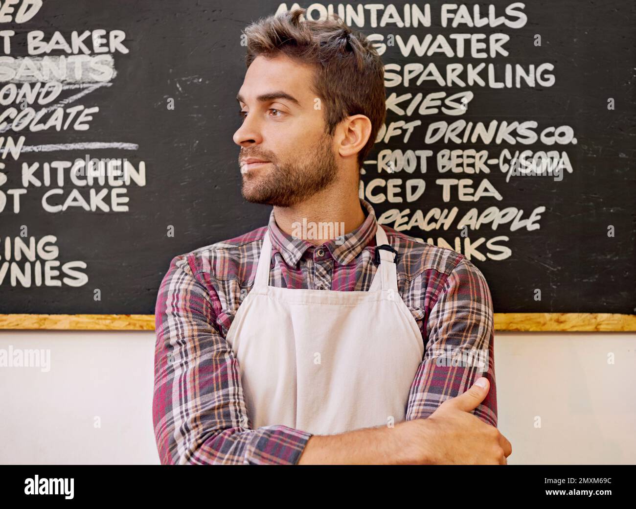 Meisterbrauer. Ein Barista steht vor einer Speisekarte, die auf einer Tafel steht. Stockfoto