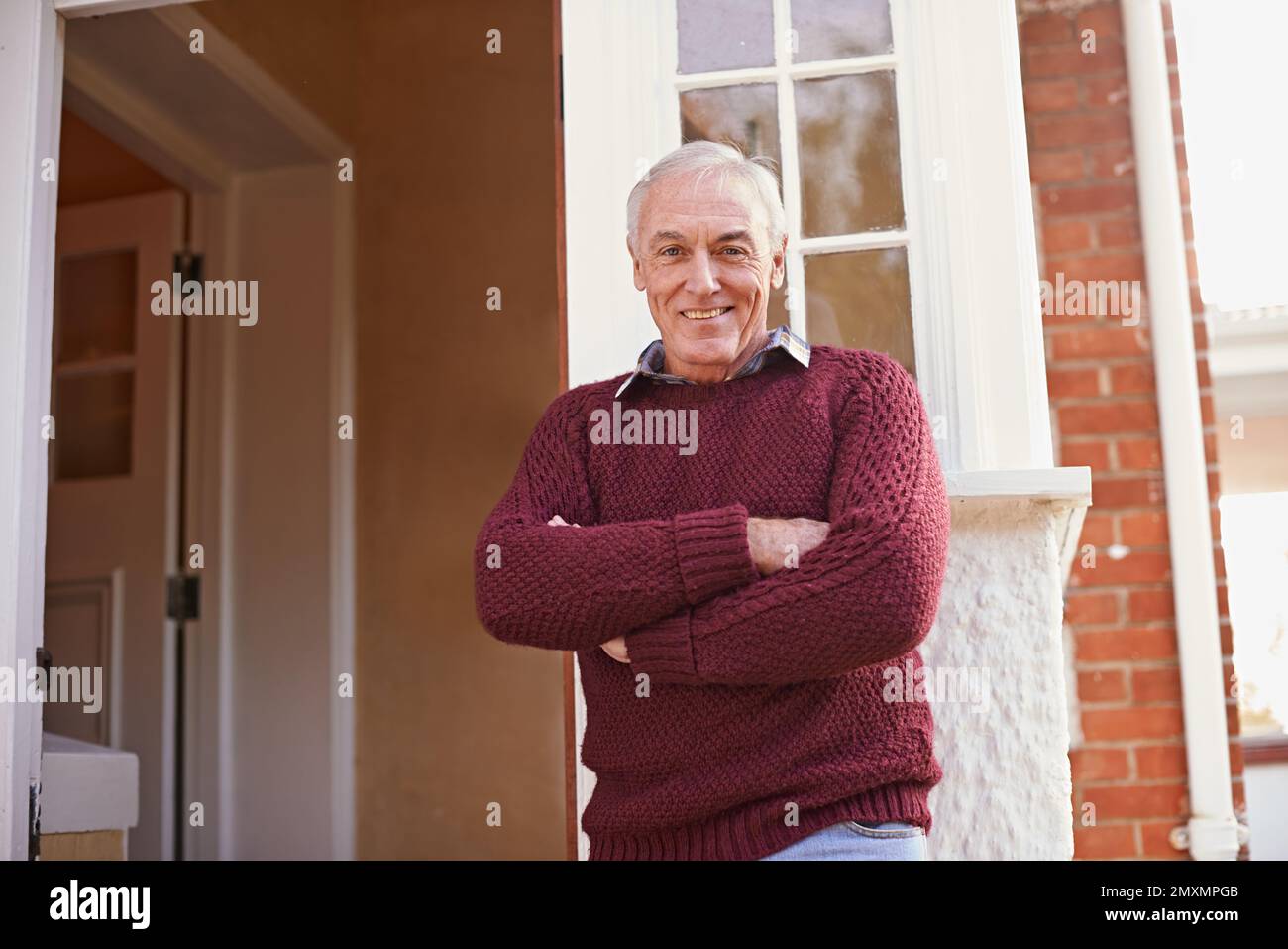 Möchten Sie zu Kommen Sie herein. Porträt eines glücklichen Seniorenmannes, der in der Nähe der Haustür zu seinem Haus steht. Stockfoto