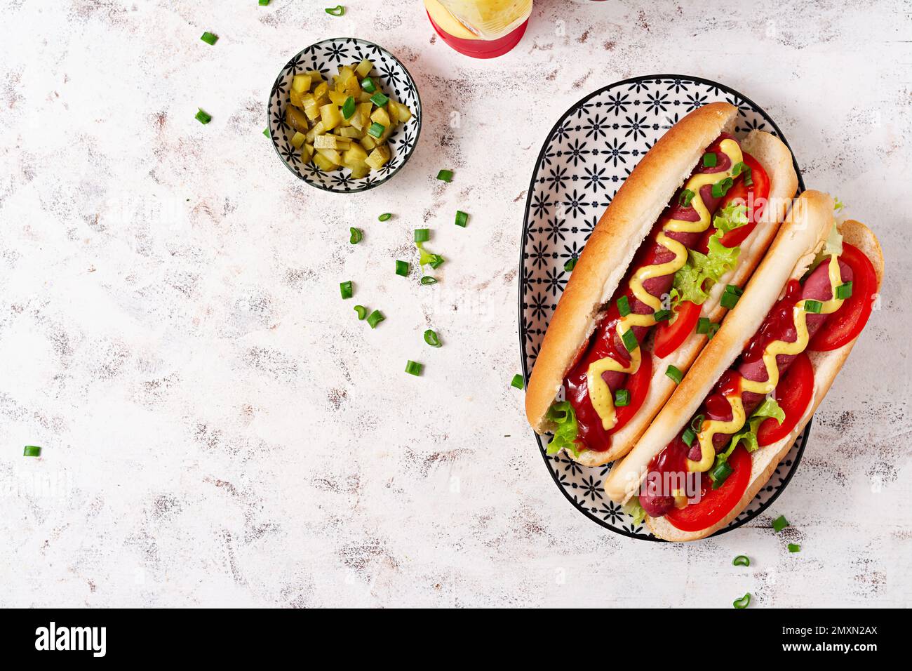 Hot Dog mit gegrillter Wurst, Tomaten und Salat auf hellem Hintergrund. Amerikanischer Hotdog. Draufsicht, über Kopf Stockfoto