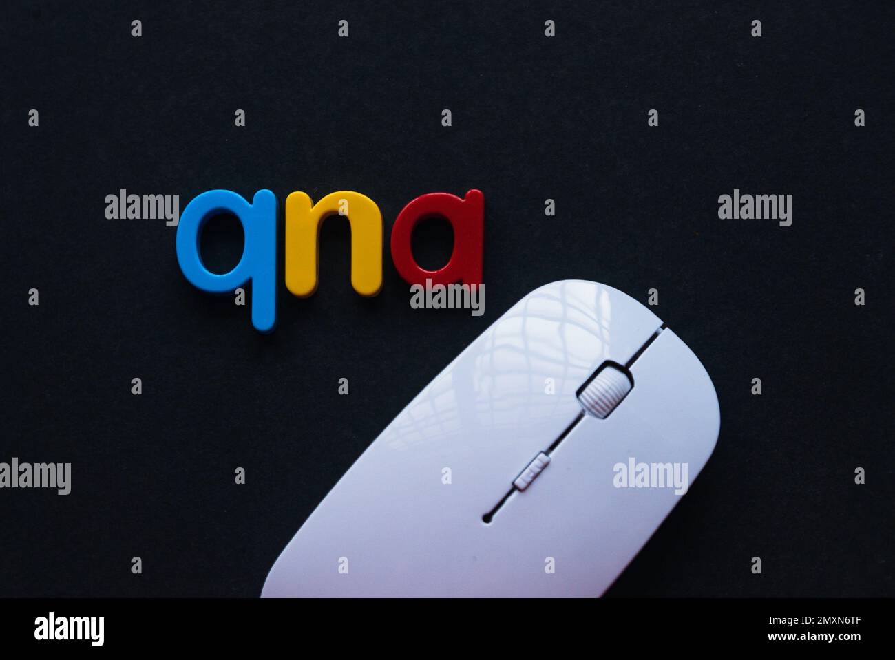 Fragen und Antworten Konzept. Das Alphabet qna und die Computermaus auf schwarzem Hintergrund. Stockfoto