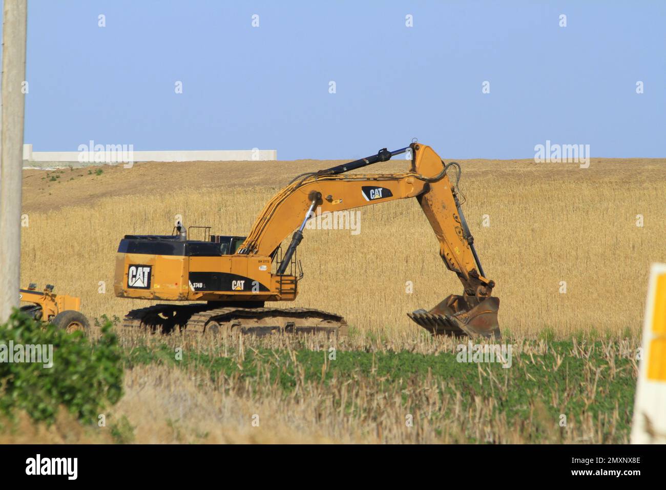 CAT-HYDRAULIKBAGGER auf einer Baustelle, die mit blauem Himmel im Land einsatzbereit ist Stockfoto