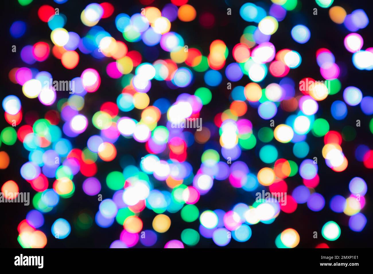 Mehrfarbige Bokeh-Kreise in Blau, Grün, Rosa, Rot und Gelb leuchten über Schwarz und schaffen einen abstrakten festlichen Hintergrund. Stockfoto