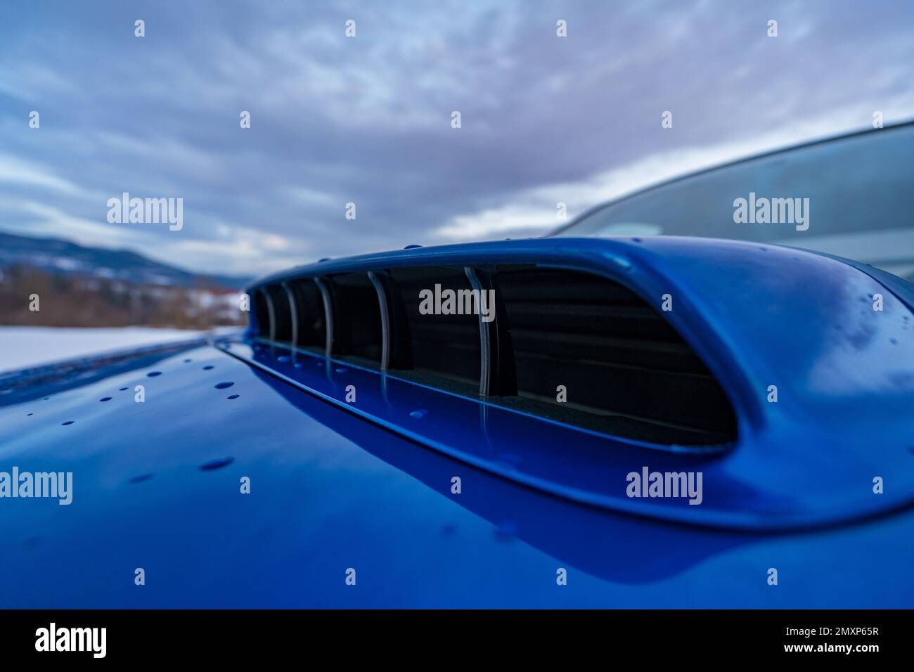 Eine Nahaufnahme der Motorhaubenschaufel eines blauen Autos. Stockfoto