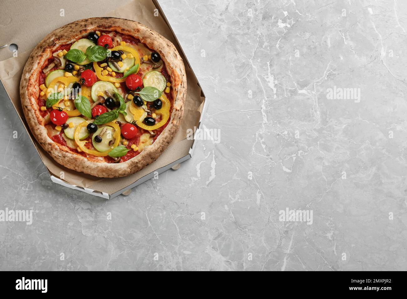Leckere Gemüsepizza in Pappschachtel auf hellgrauem Tisch, Draufsicht. Platz für Text Stockfoto